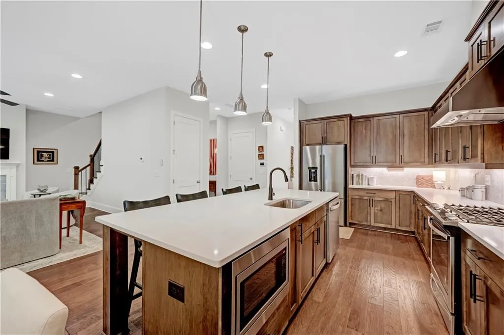 Kitchen featuring a breakfast bar area, stainless steel appliances, backsplash, decorative light fixtures, and recessed lighting