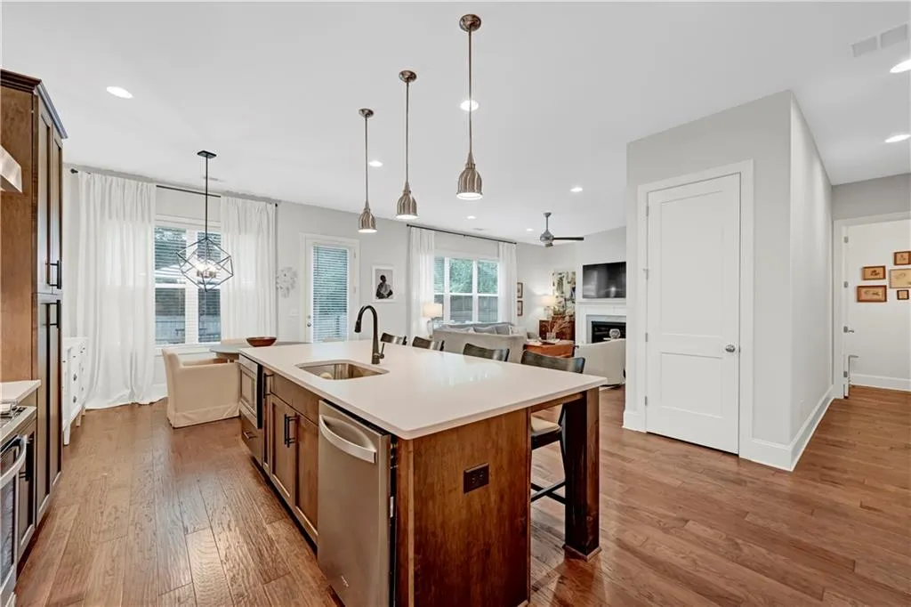Kitchen with a fireplace, a kitchen bar, brown cabinetry, appliances with stainless steel finishes, and a center island with sink
