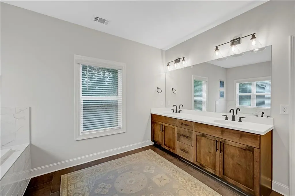 Bathroom featuring double vanity, plenty of natural light, and tiled tub