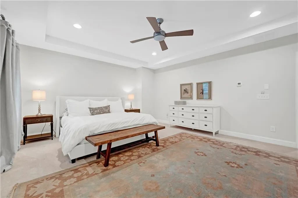 Bedroom featuring light carpet, a raised ceiling, ceiling fan, recessed lighting, and a barn door