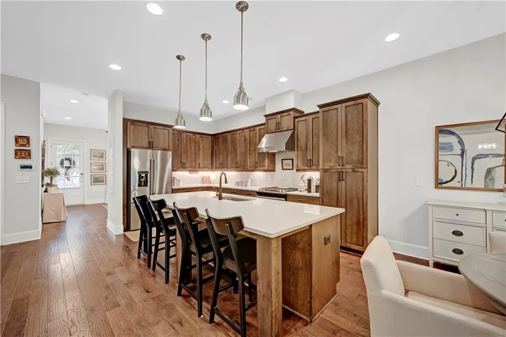 Kitchen with a kitchen bar, a center island with sink, brown cabinets, stainless steel appliances, and light wood-style floors