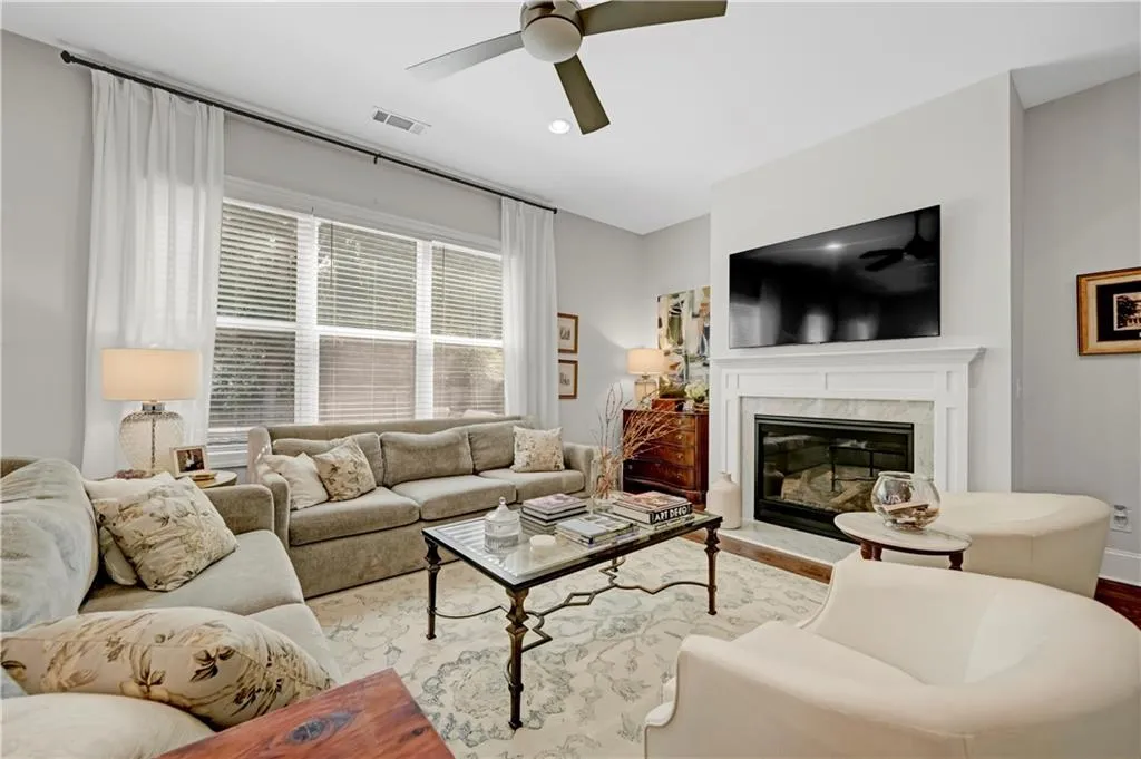 Living room featuring a high end fireplace, ceiling fan, recessed lighting, and wood finished floors