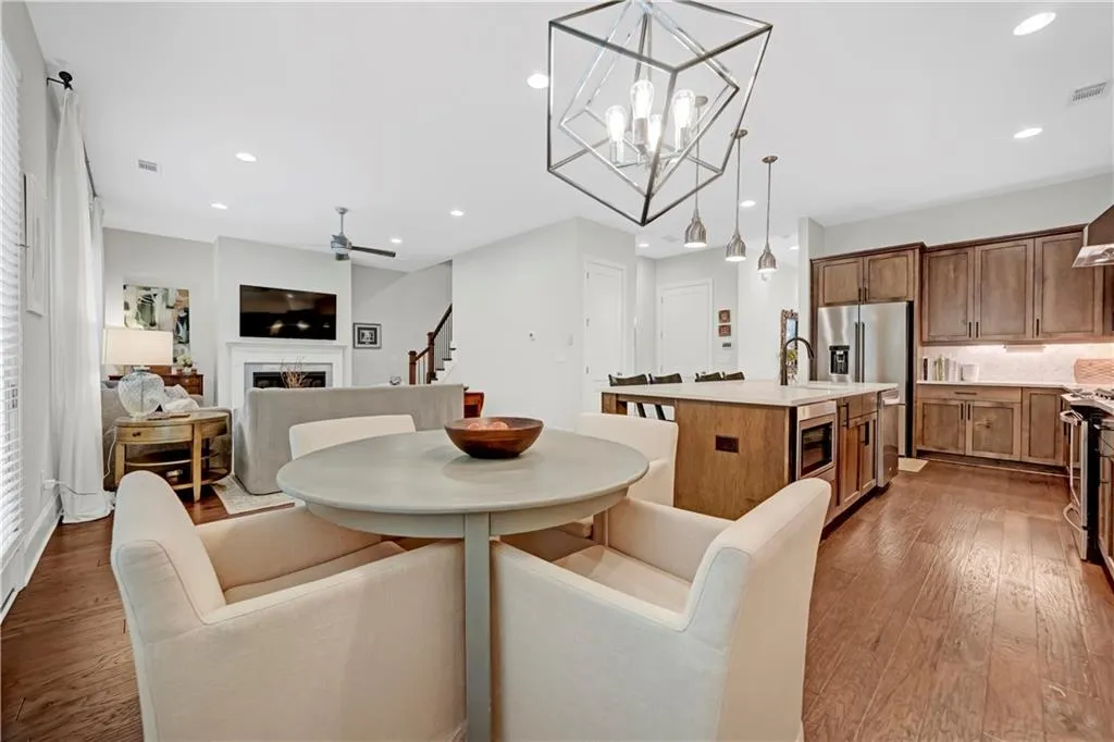Dining room featuring light wood-style flooring, a fireplace, ceiling fan, recessed lighting, and stairs