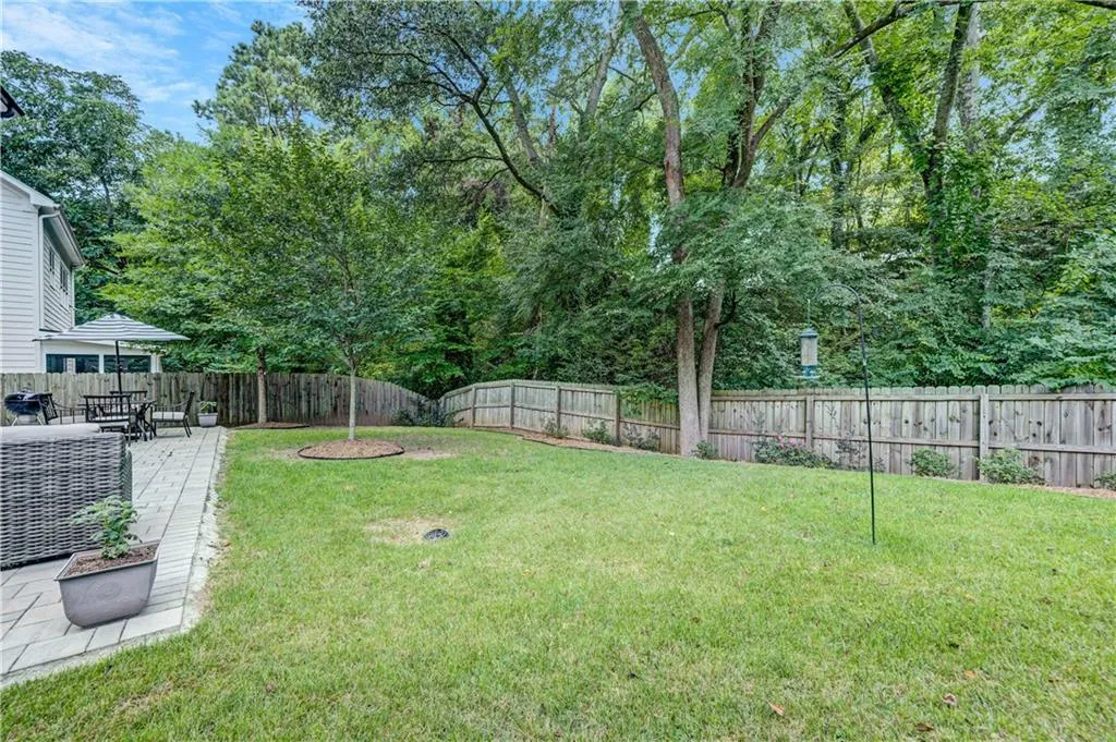 Fenced backyard featuring a patio area and view of scattered trees