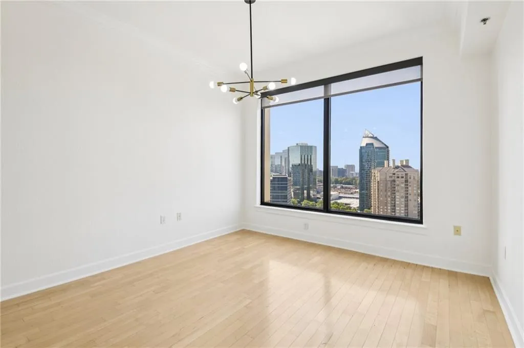 Unfurnished room with a view of skyline, a chandelier, light wood-style flooring, and ornamental molding