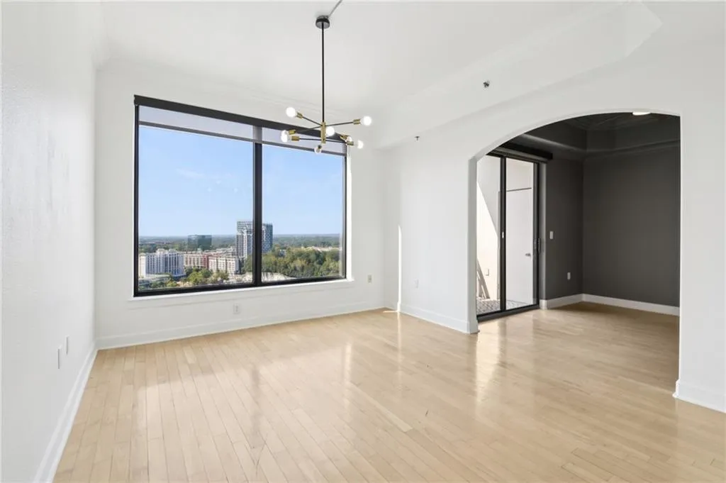 Unfurnished dining area featuring arched walkways, ornamental molding, a chandelier, light wood finished floors, and a city view