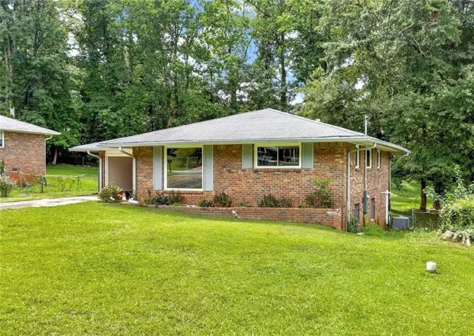 Brick exterior featuring a hip roof, broad front windows, and an integrated carport