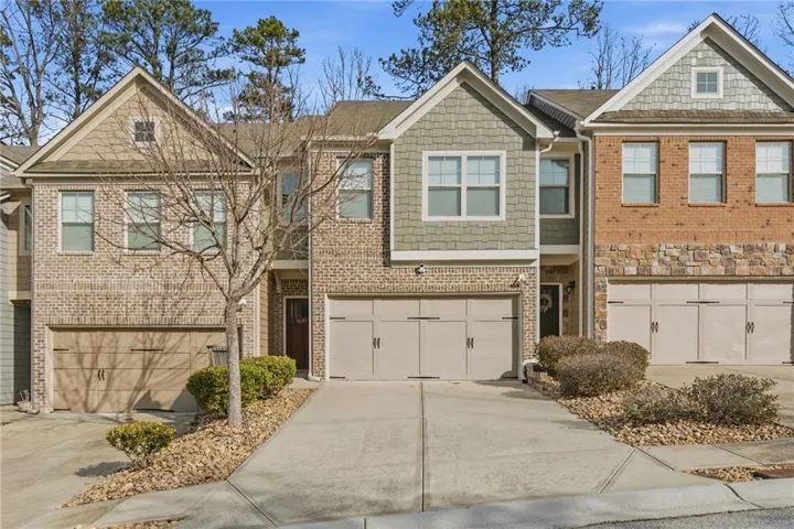 Brick and shingle exterior featuring a two-car garage with a concrete driveway