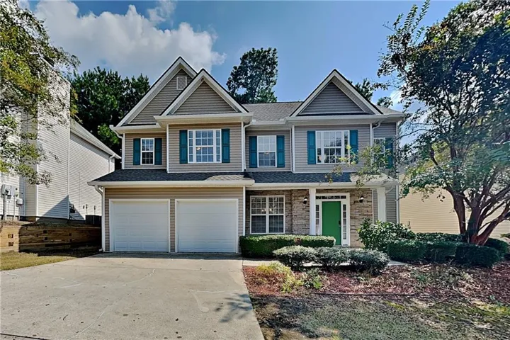 Two-story residence featuring a two-car garage, stone facade accents, and a covered entry