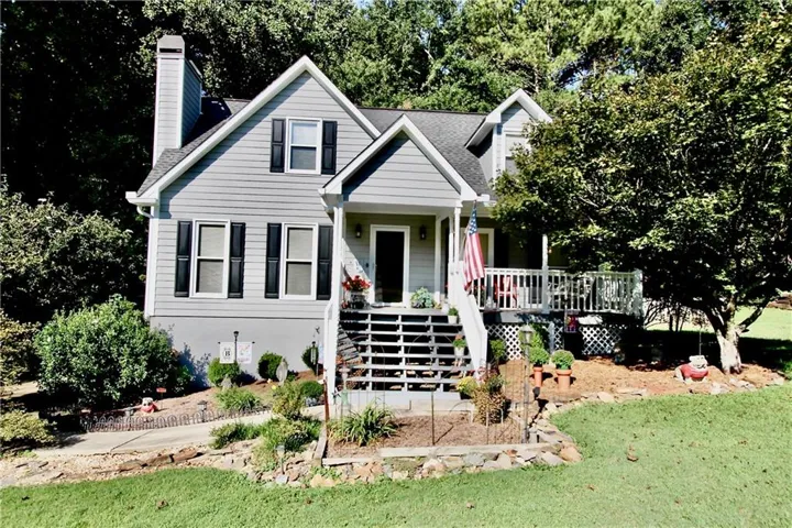 Gable roofline, light gray siding exterior, white trim, front porch, and elevated deck