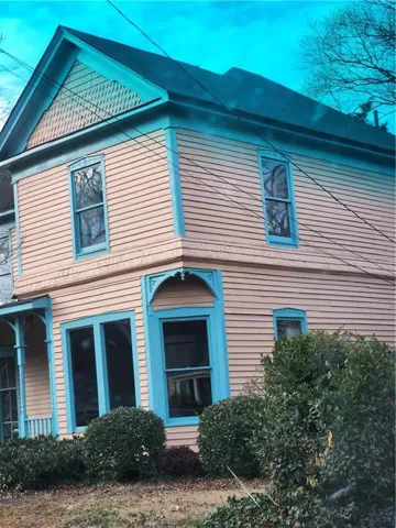Two-story exterior with horizontal siding, multiple window styles, and decorative trim
