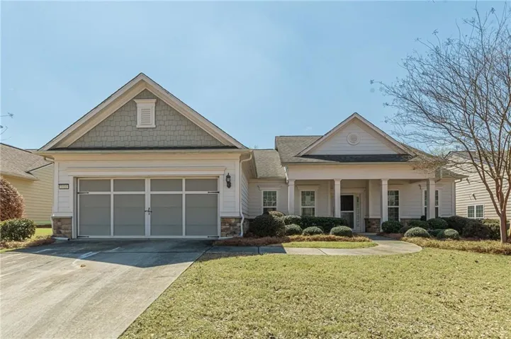 Craftsman-style house featuring a porch, stone siding, driveway, a front lawn, and a garage