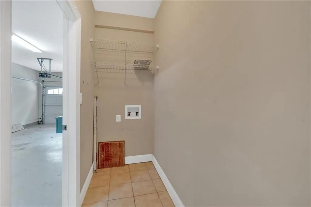 Clothes washing area with light tile patterned floors, washer hookup, baseboards, and laundry area