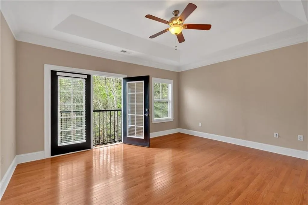 Empty room featuring light wood-type flooring, baseboards, visible vents, and a raised ceiling