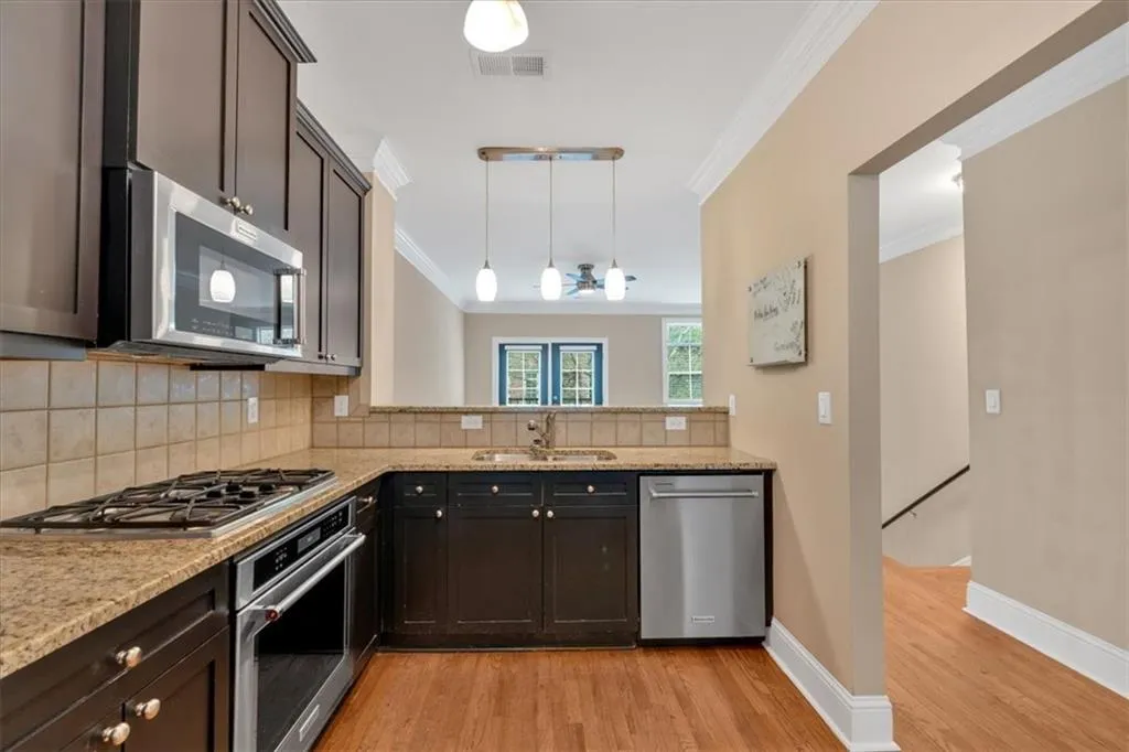 Kitchen with a sink, appliances with stainless steel finishes, light wood-style flooring, ornamental molding, and visible vents