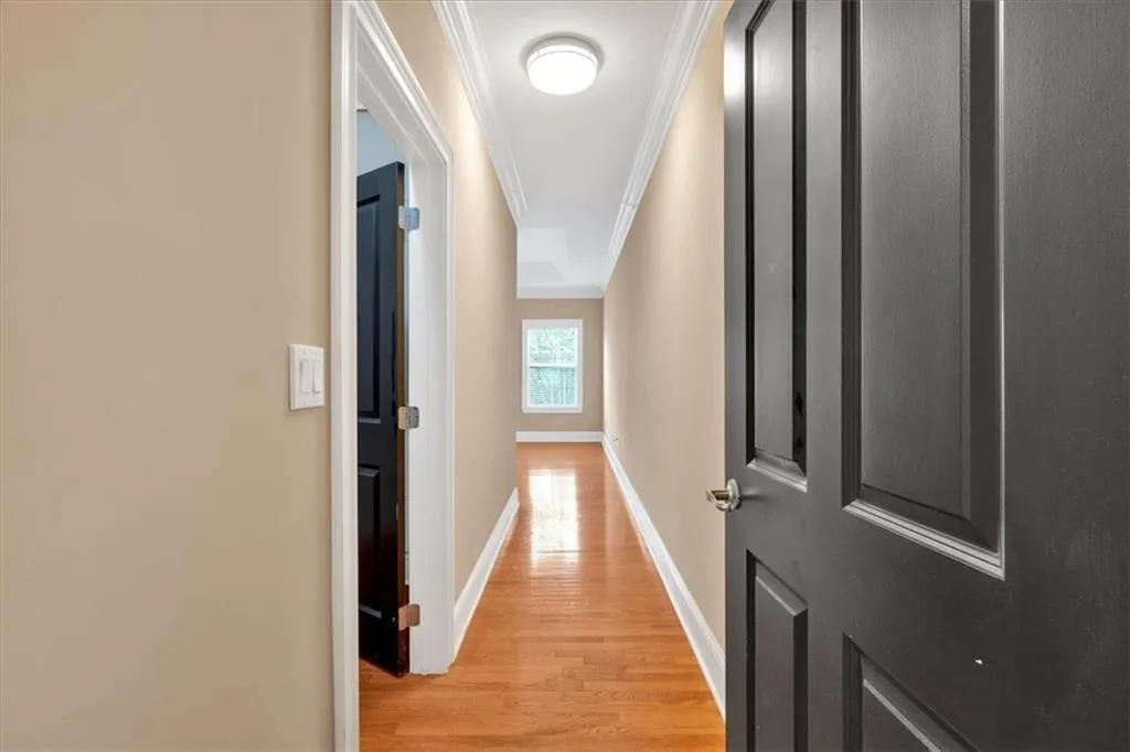 Hall with light wood-type flooring, baseboards, and ornamental molding