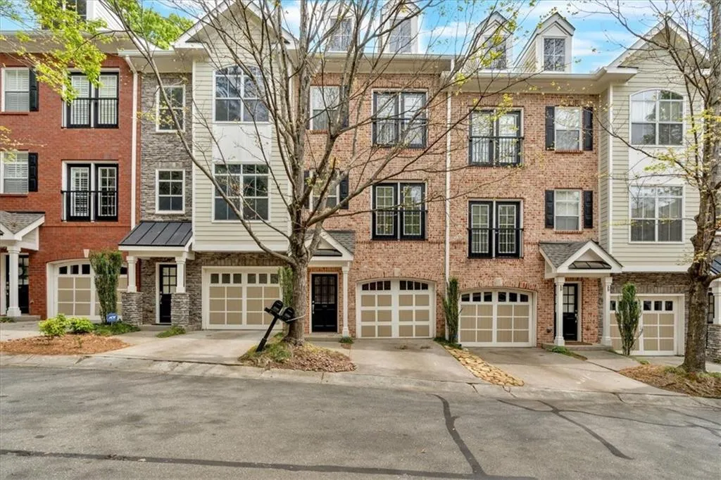 Townhome / multi-family property featuring brick siding, an attached garage, and driveway