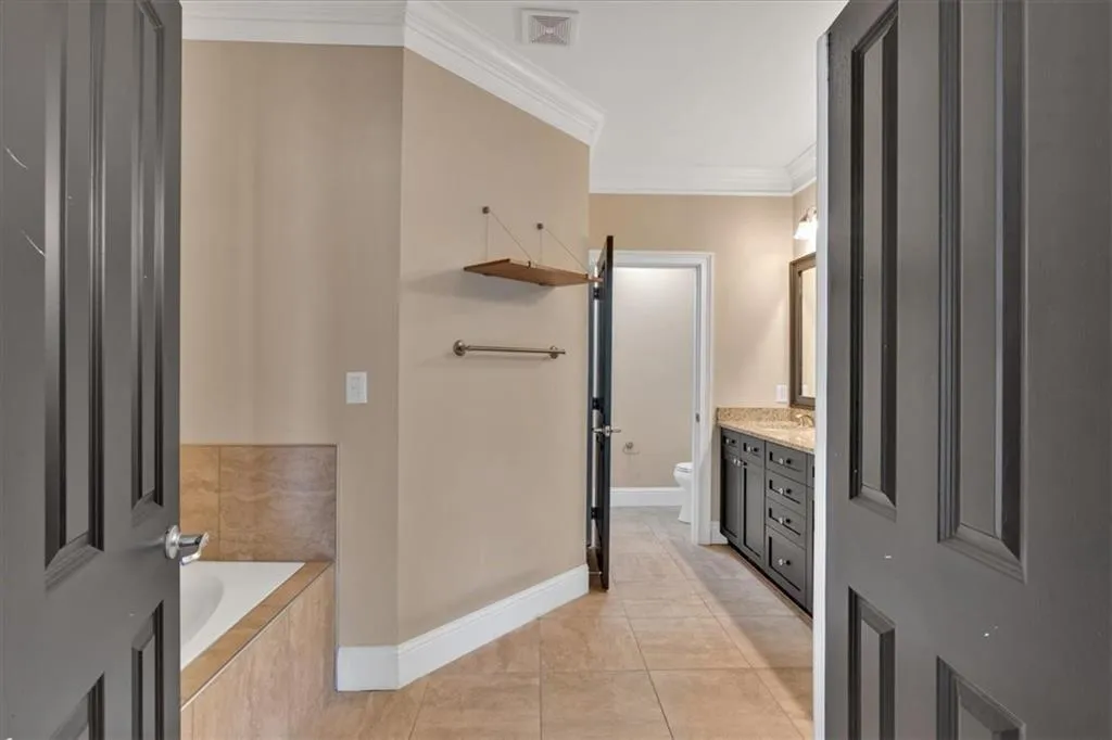 Bathroom featuring toilet, visible vents, tile patterned flooring, vanity, and ornamental molding