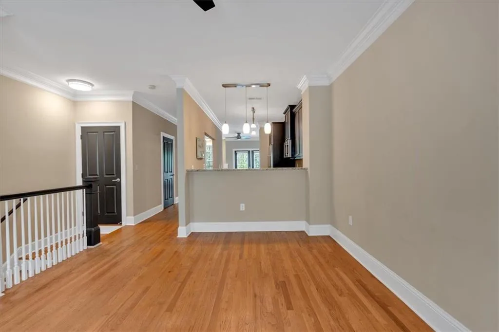 Spare room featuring light wood-type flooring, baseboards, an inviting chandelier, and crown molding