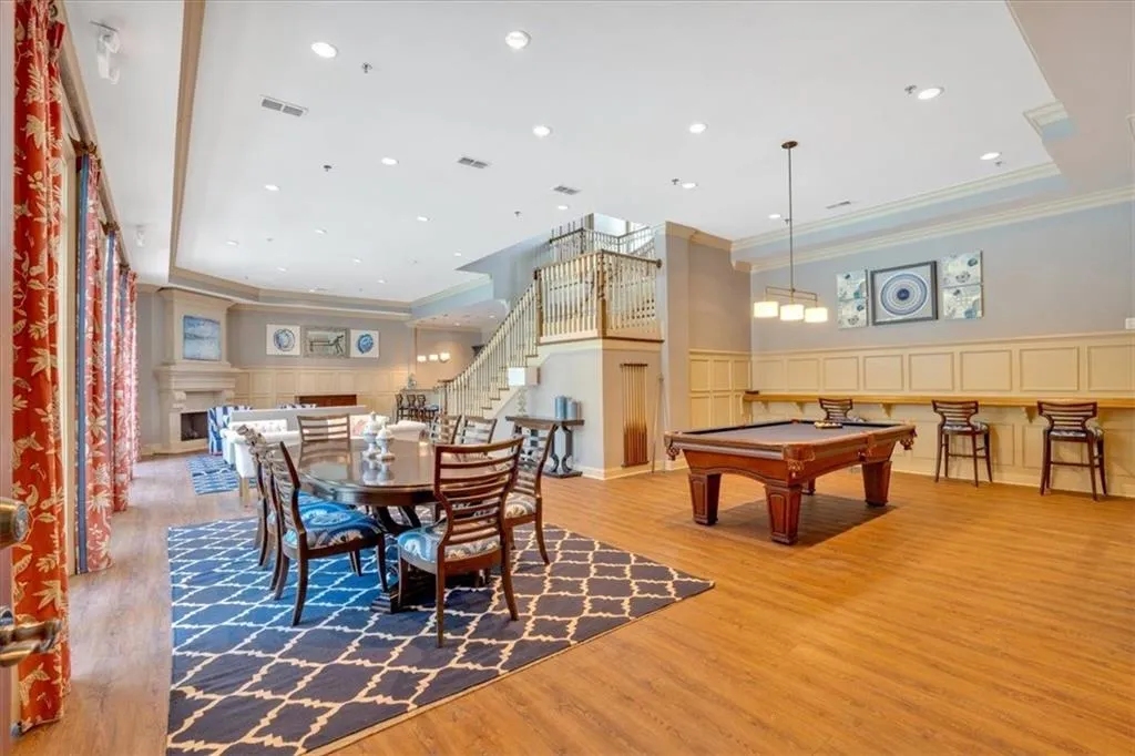 Playroom featuring a decorative wall, wood finished floors, wainscoting, ornamental molding, and visible vents