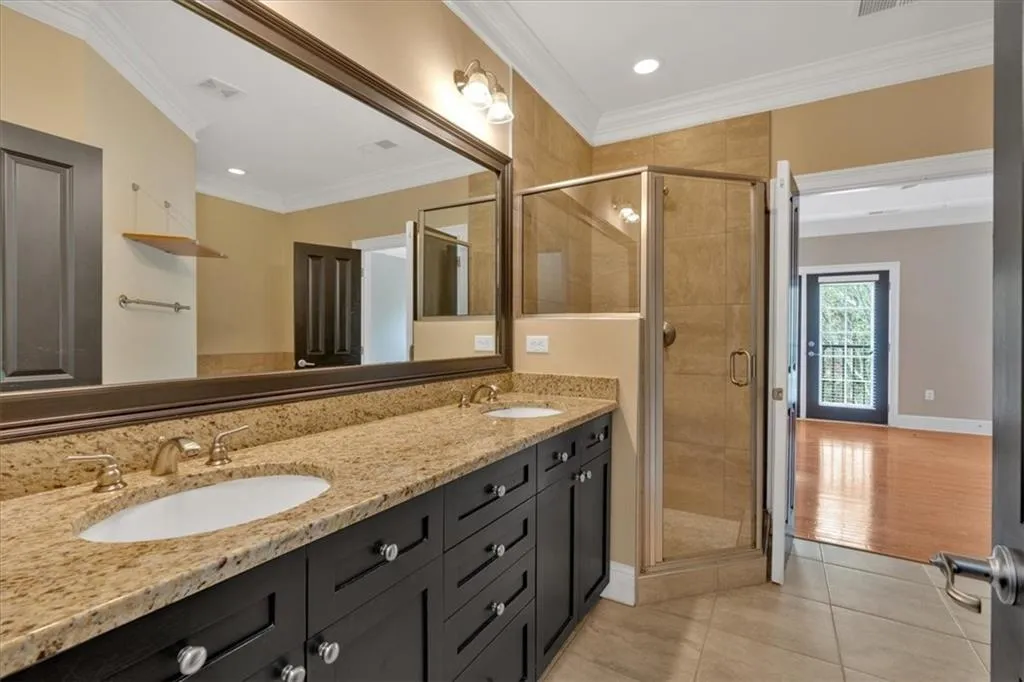 Bathroom with crown molding, tile patterned flooring, a sink, and a stall shower