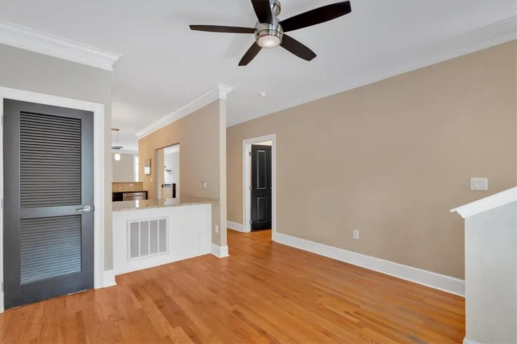 Unfurnished living room featuring crown molding, ceiling fan, light wood finished floors, baseboards, and visible vents