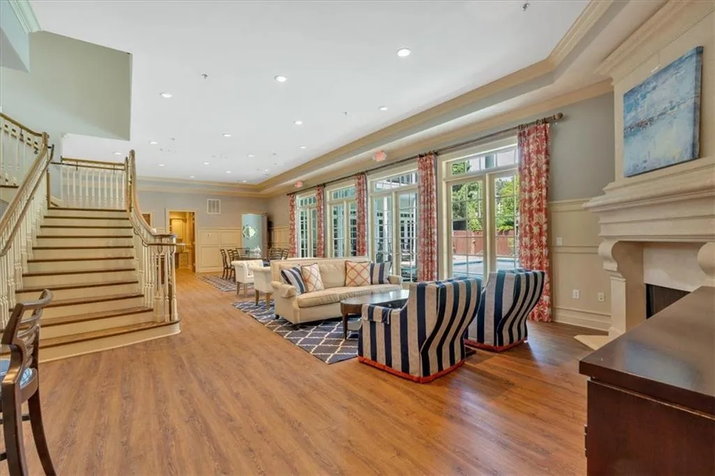 Living area with wood finished floors, a decorative wall, stairs, and ornamental molding