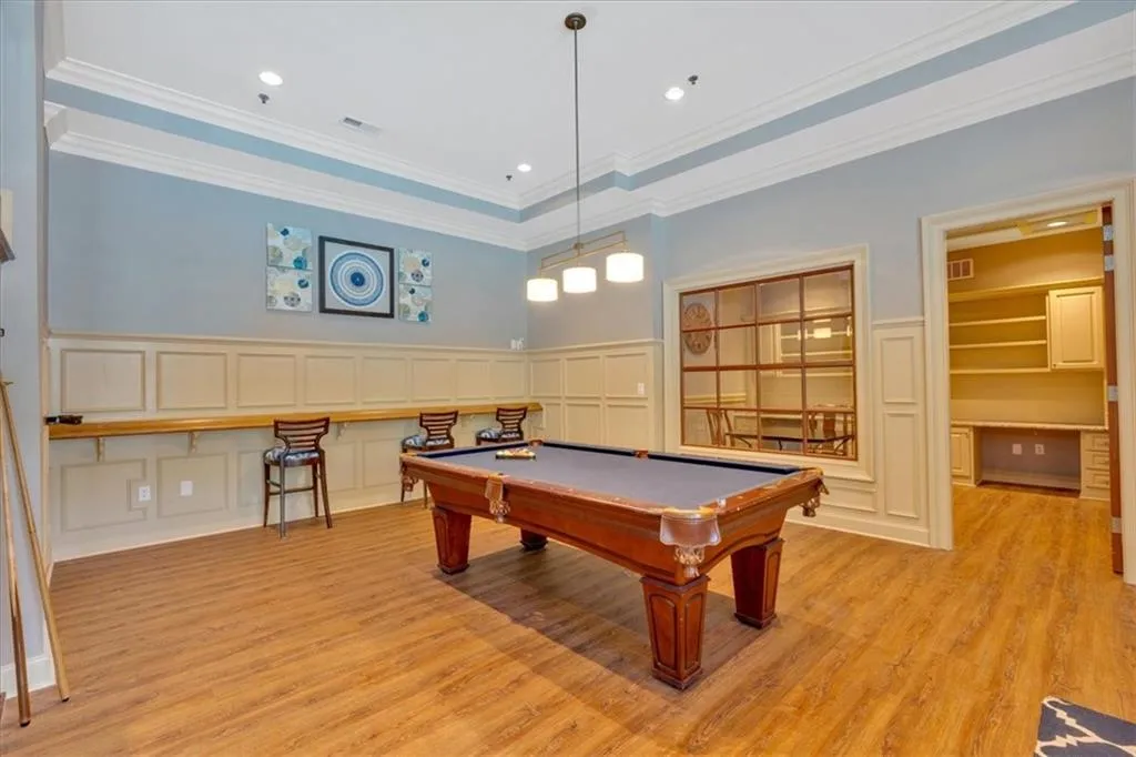 Game room featuring light wood-style flooring, ornamental molding, and a decorative wall