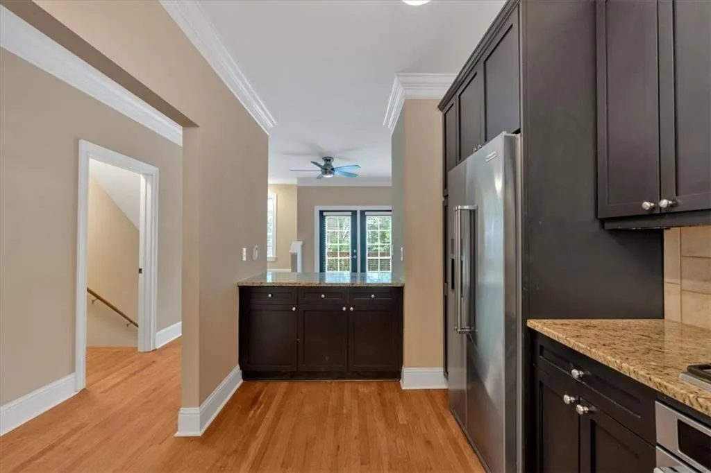Kitchen with baseboards, light wood-style floors, appliances with stainless steel finishes, light stone countertops, and ornamental molding