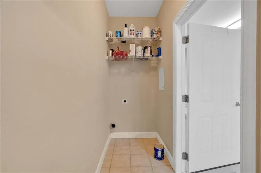 Laundry area with light tile patterned floors, baseboards, laundry area, and hookup for an electric dryer