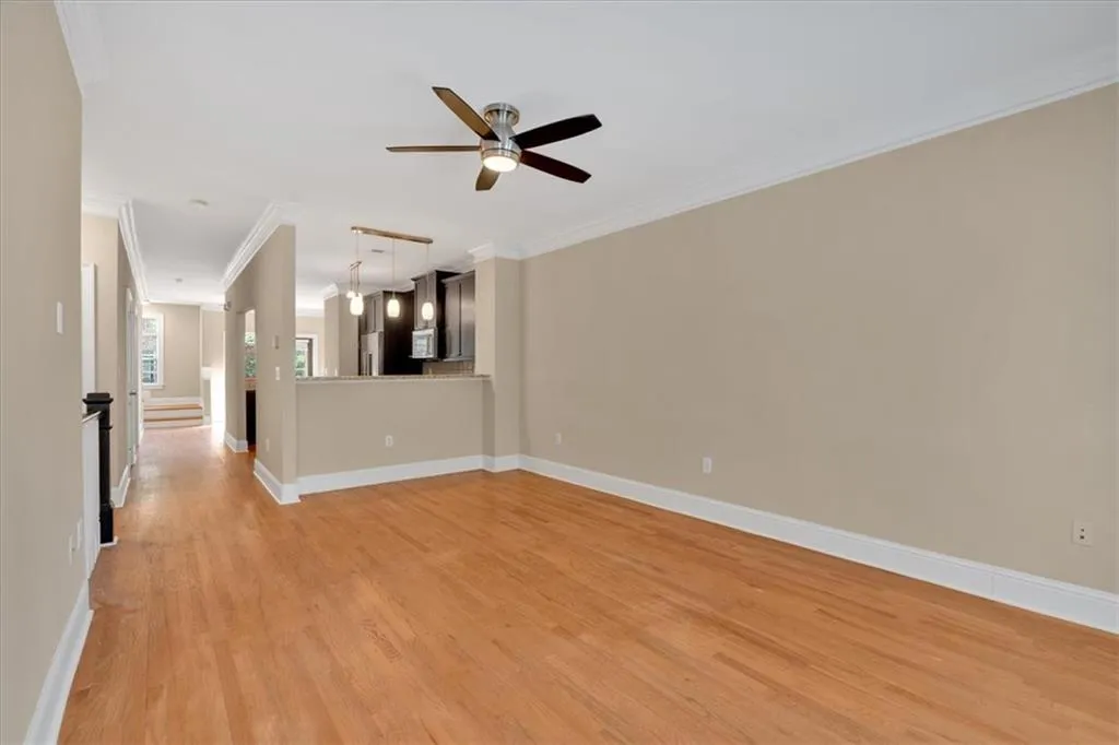Unfurnished living room with baseboards, light wood-style floors, ceiling fan, and crown molding
