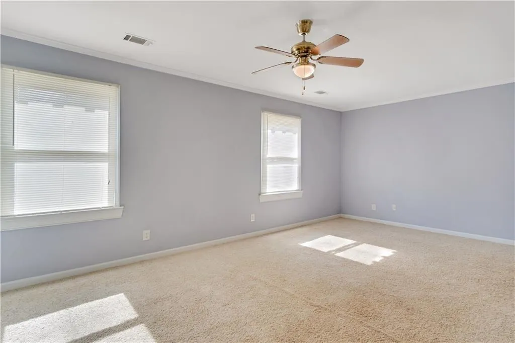 Spare room featuring visible vents, carpet floors, and ornamental molding