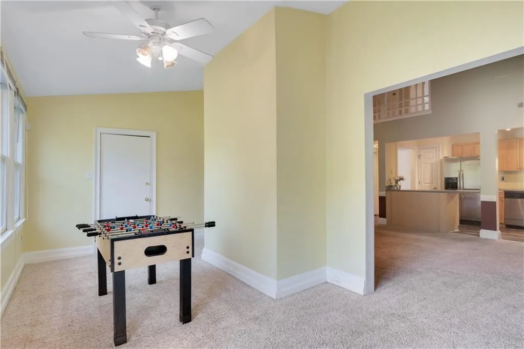 Playroom with light carpet, high vaulted ceiling, baseboards, and ceiling fan
