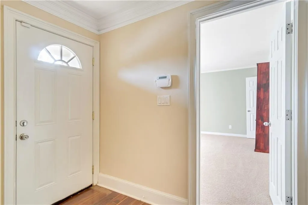 Carpeted foyer entrance featuring baseboards and crown molding