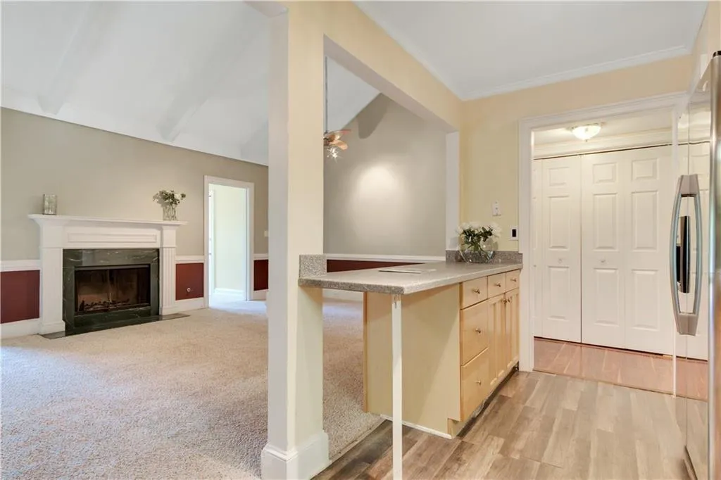Kitchen featuring a high end fireplace, light wood finished floors, vaulted ceiling with beams, light countertops, and stainless steel refrigerator