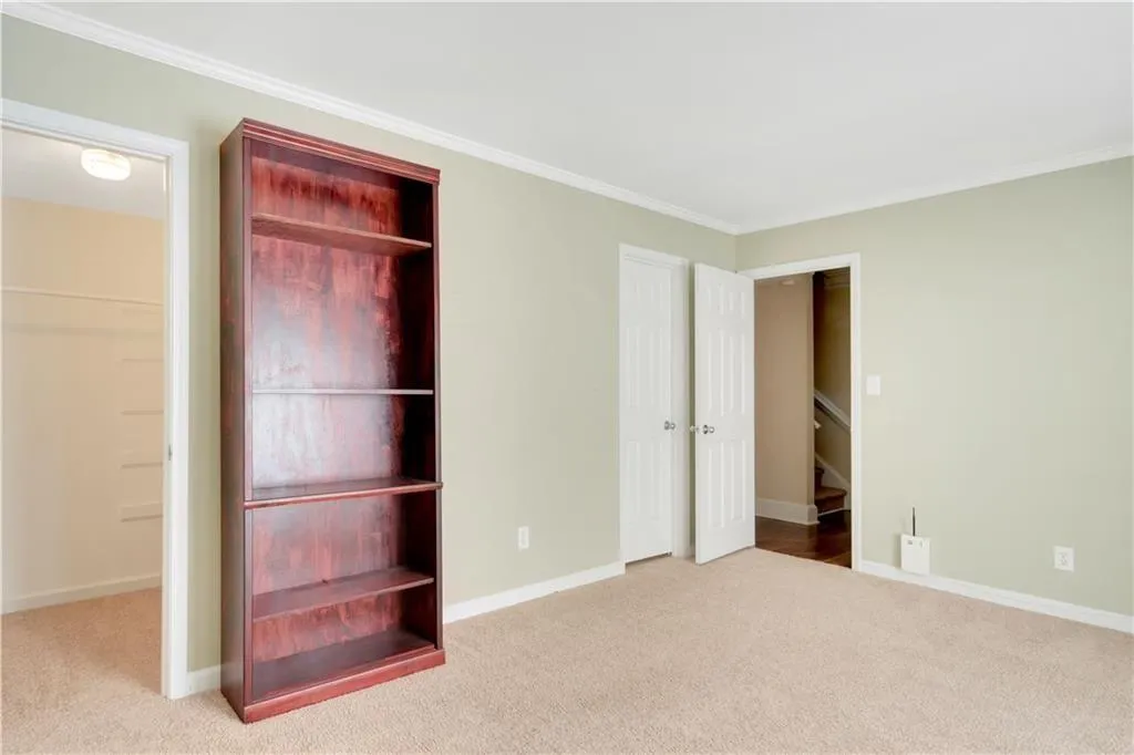 Unfurnished bedroom featuring carpet flooring, crown molding, and baseboards
