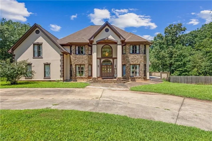 Stucco and stone exterior featuring multiple gables and a two-story arched entry