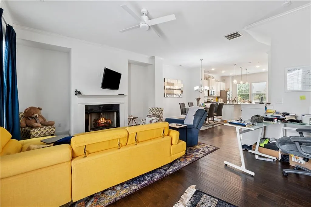 Living room with ceiling fan, wood finished floors, a warm lit fireplace, a chandelier, and recessed lighting