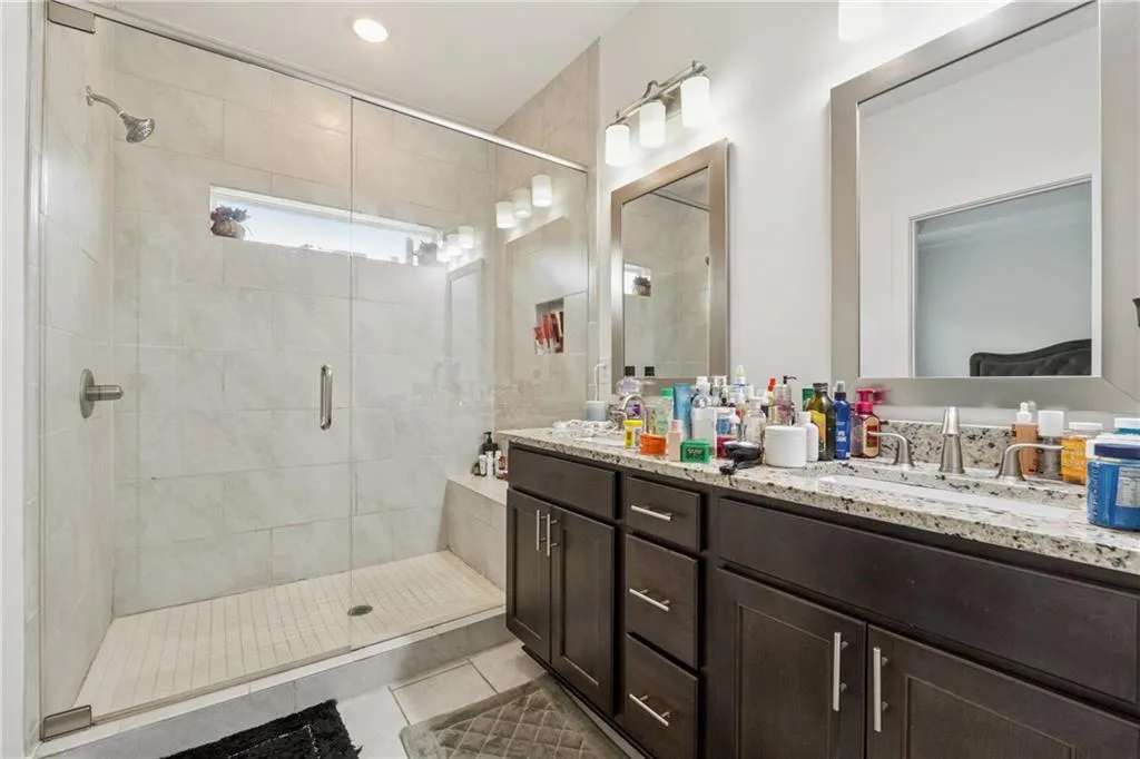 Bathroom with double vanity, a shower stall, and tile patterned flooring