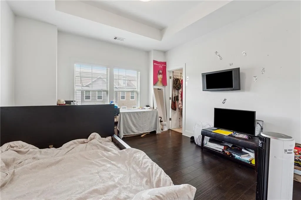 Bedroom with wood-type flooring and a raised ceiling