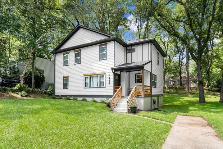 View of front of property with a front lawn, view of wooded area, and a porch
