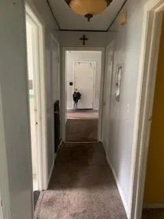 Hallway with carpet floors and baseboards