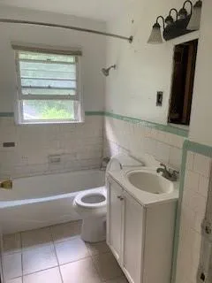 Bathroom with tile walls, a bathtub, vanity, tile patterned floors, and a wainscoted wall