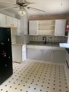 Kitchen featuring open shelves, backsplash, refrigerator, a ceiling fan, and light floors
