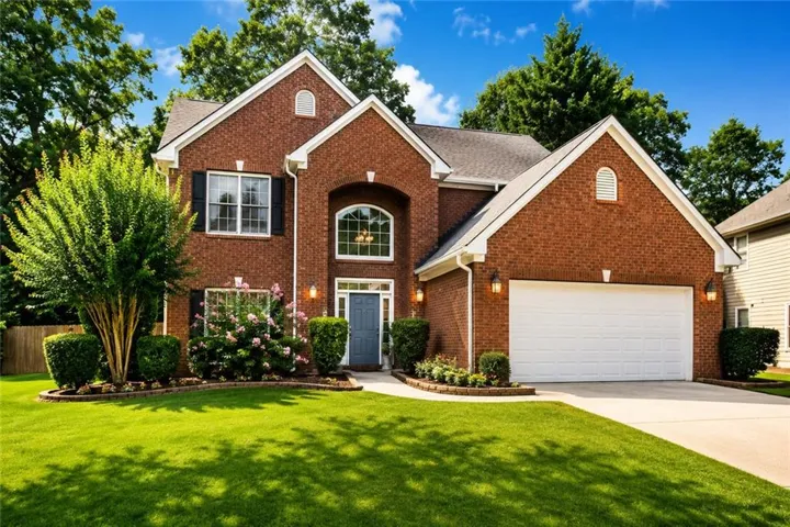 Brick facade with a gabled roofline, arched window, and a two-car garage