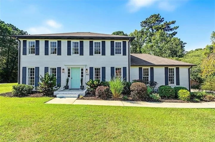 White siding exterior with dark shutters, light blue entry door, and a multi-level roofline