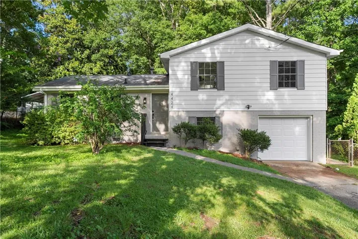 Split-level residence featuring a white siding upper facade and a painted brick lower level