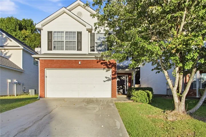 Two-story exterior featuring brick and siding, a two-car garage, mature landscaping, and an inviting entry