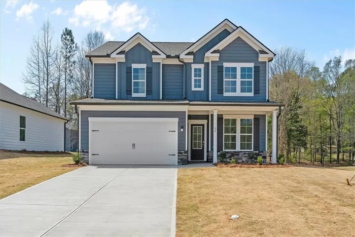Two-story residence featuring blue siding with white trim accents, a prominent front entry with a covered porch, a two-car garage, and stone facade detailing