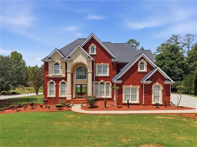 Stately brick exterior featuring a grand arched entryway, multiple gabled rooflines, and decorative window trim